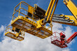 © K - Elevated boom lift baskets with guardrails and articulated support arms show access equipment, illustrating temporary work platforms for construction and building maintenance