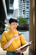 © Davor - Businesswoman using voice assistant on smartphone in city