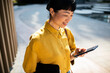 © Davor - Smiling businesswoman using smartphone outdoors in city