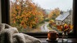 © Marusha - Cozy autumn window view with a steaming mug, knitted blanket, and fall leaves in a vase