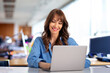 © sepy - Smiling businesswoman sitting with laptop in the office