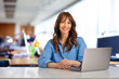 © sepy - Smiling businesswoman sitting with laptop in the office