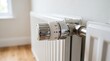 © MyDigitalCraft - Close-up of a radiator valve, Home radiator with thermostat knob in a bright room with wooden floor