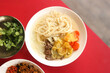 © Tantri - A plate of Indonesian-style sup misoa, thin wheat noodles in a clear savory broth. Each portion includes tender beef, slices of carrot, and crispy potato chips.