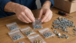 © Momin - Person sorting hardware and organizing various metal screws into small plastic bags with wooden table hardware organizing fasteners components assembly workshop maintenance equipment
