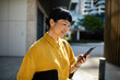© Davor - Smiling professional woman using smartphone outdoors in city