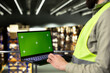 © DC Studio - Green screen laptop sits near warehouse staff handling packages for logistics and distribution, with manual labor supporting shipping management.