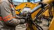 © KH Studio  - A mechanic wearing workwear and gloves uses an adjustable wrench to repair heavy machinery in a workshop.