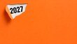 © Pixelpoint - The year 2027 is printed on a sheet of paper, adorned with a peeling orange cover, symbolizing fresh business plans and solutions for the new year. The typography highlights 2027.