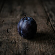© Reading - Single Black Apple on Rustic Wooden Surface.