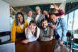 © CarlosBarquero - Multicultural coworkers laughing during a lively office meeting, showcasing teamwork, friendship, success, and a vibrant corporate atmosphere.