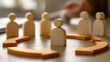 © Kowit - Wooden human figures arranged in a circle, symbolizing teamwork, leadership, and collaboration in a professional or organizational context.