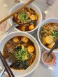 © Verisa - Three bowls of spicy Chinese Mala soup with dipping sauce on table, traditional Sichuan hot pot dish