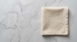 © NorthStar Creations - Folded beige linen napkin on a light gray marble table surface with copy space.