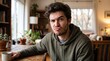 © Gabriel - Young man with skeptical expression holding a coffee mug at a wooden table