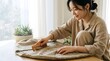© SITI - Smiling Asian woman brushing knit sweater with wooden comb on table at home