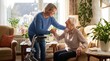 © Jelsi - A caring woman helping an elderly senior lady stand up from her chair at home.