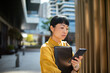 © Davor - Professional woman checking smartphone outside modern office building