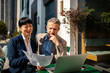 © Davor - Two business professionals reviewing documents at outdoor cafe