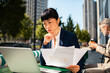 © Davor - Businesswoman analyzing financial report on laptop at outdoor city cafe