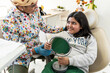 © Manu Prats/Stocksy - Girl smiling at dentist holding mirror in pediatric clinic