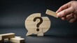 © Shahbaz - Hand placing wooden block onto puzzle shaped like speech bubble with question mark on a dark background in studio light
