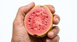 © Marlon - Close up of a hand holding a ripe pink guava fruit cut in half revealing juicy flesh and seeds isolated on white summer