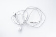 © Meekarn - Top-down view of messy tangled white wired earphones isolated on a white background representing frustration and disorganized technology.