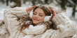 © S-DESIGN - A young woman wearing headphones, enjoying a peaceful moment outdoors in a snowy environment, wrapped in a cozy knitted blanket. Her eyes are closed, and a gentle smile graces her face.