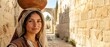 © xuxu - Young woman carrying water jar on head through ancient middle eastern banner format