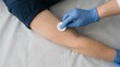 © SimpleDesignStudio - Medical professional disinfecting adult caucasian male arm with cotton pad prior to injection or blood draw in clinic
