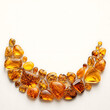 © Nichapa888 - Elegant overhead composition of assorted amber gemstones arranged in a sophisticated crescent shape along the lower edge of a pristine warm-white background
