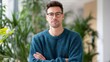 © evgenia_lo - Stylish Young Man in a Cozy Sweater Posing Confidently Against a Lush Greenery Background in a Modern Indoor Setting