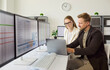 © Studio Romantic - Analysts and businesswoman review finance data on monitors. Colleagues work at a laptop in bright office comparing spreadsheets and charts to assess analytics. Teamwork fuels data led choices.