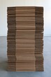 © jhx studio - A tall stack of flat brown cardboard boxes inside a bright warehouse space