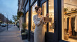 © PrabuanaAndika - Female entrepreneur hanging open sign on boutique door at dusk