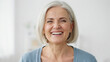 © kobita Art - Close-up portrait of a happy senior woman with short gray hair smiling brightly at the camera.