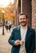 © Nei Mar - Smiling man with a mustache holding a cup in an autumn cityscape