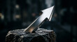 © masyitahagus - Chrome arrow pointing upwards embedded in a dark rugged stone against a blurred background