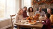 © jelsi - Happy multi-generational family enjoying a festive Thanksgiving dinner together at home.