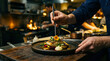 © musab - Professional chef plating a gourmet fish dish with tweezers in a busy restaurant kitchen