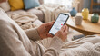 © NK - Senior woman texting on smartphone at home, elderly hands holding mobile phone with blank chat bubbles and red heart on cozy sofa for family communication, social app and online dating