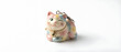 © Yuliia - Colorful ceramic lucky cat figurine with smiling expression, raised paw gesture, and decorative bells