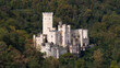 © Amazing Aerial - Aerial view of Stolzenfels Castle nestled in a dense forest, featuring its distinctive white towers, gothic architecture, and stone walls in Koblenz, Rheinland-Pfalz, Germany.