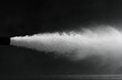 © krisna - High-pressure water jet spraying outward from a dark nozzle against a dark background