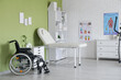 © Pixel-Shot - Interior of physiotherapists office with couch, wheelchair and shelf unit