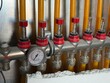 © Tetyana - Heating manifold feeding yellow pex underfloor heating circuits with red flow meters, control valves and a thermometer showing water temperature in new residential installation