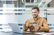 © Liubomir - Online shopping and e commerce success, happy man using credit card for payment on laptop in office. Digital banking and financial transaction, professional person completing purchase with excitement.