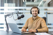 © Liubomir - Podcaster recording audio content in office, man using microphone and laptop for digital broadcasting and remote communication. Professional creator producing media with headset and computer.