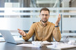 © Liubomir - Work stress and burnout, frustrated businessman gesturing at desk with laptop and crumpled paper in office. Professional employee struggling with deadline pressure and heavy workload.